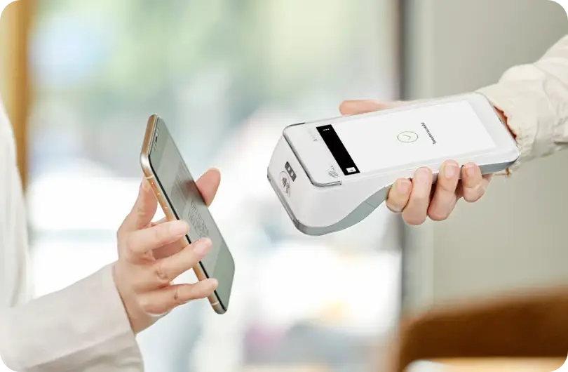 A customer paying by phone against a handheld card terminal